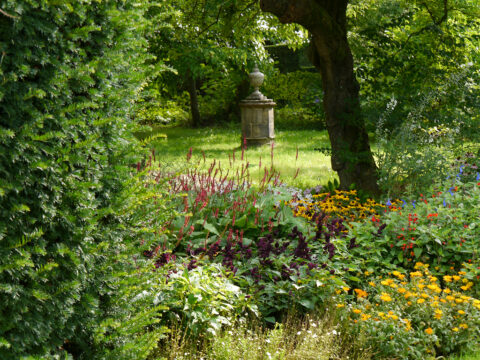 Blick vom Doppel-Mixed-Border zu einem der Familien Memorial, Nymans Garden