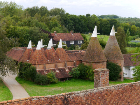 Blick vom Turm auf das ausserhalb des Gartens gelegene Gebäudeensemble - Oast House (Darre), Elisabethanische Scheune, Restaurant und Souvenir-Laden 